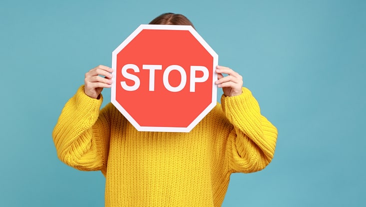 Eine Person hält ein Stop-Schild vor dem Gesicht